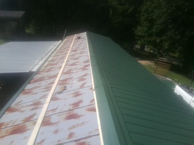 Old rusted panels beside newly installed green metal roofing — Wind Damage Roof Repair by Roofing Brothers in Worley