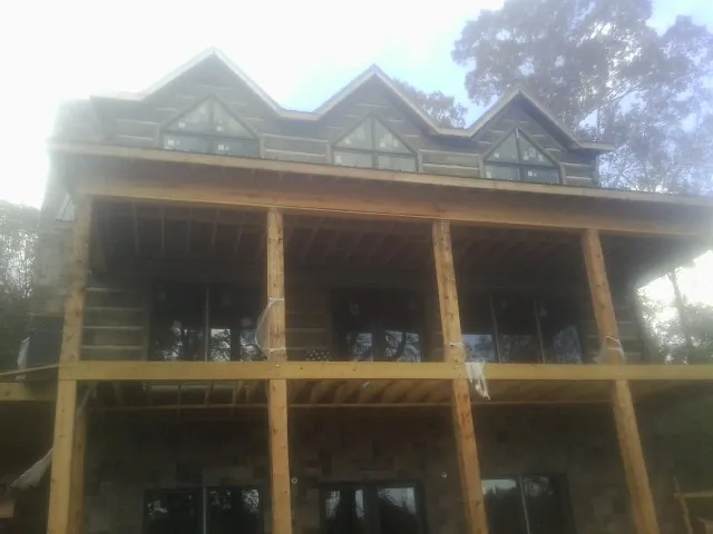 Dormers and porch framing on a large log home under construction — Roof Coating work by our crew in Worley