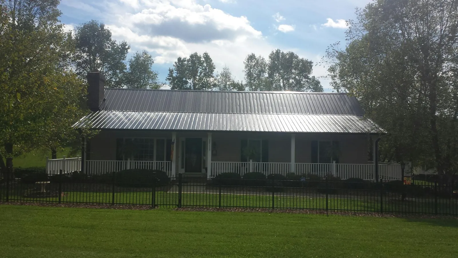 Gray metal roof on a brick ranch with a full width front porch — Gutter Guard Installation work by our crew in Worley