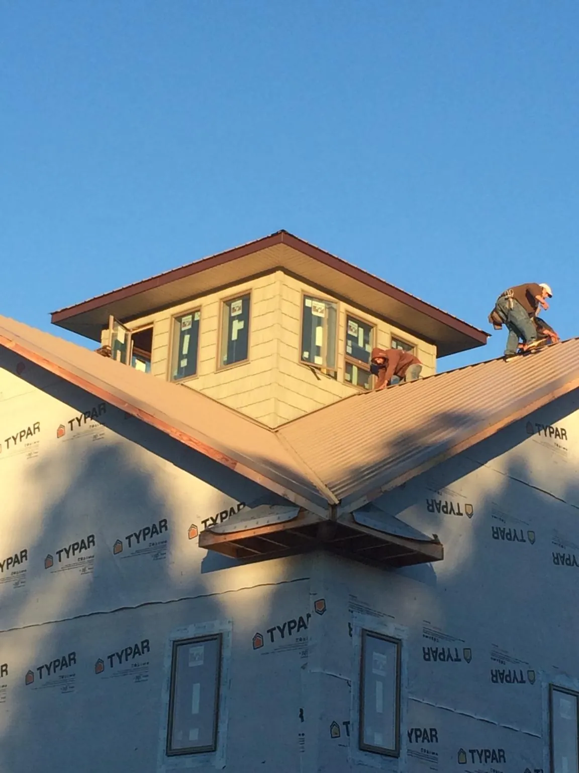Roofers working around a rooftop cupola on a new metal roof at sunset — Roof Waterproofing in Worley by Roofing Brothers